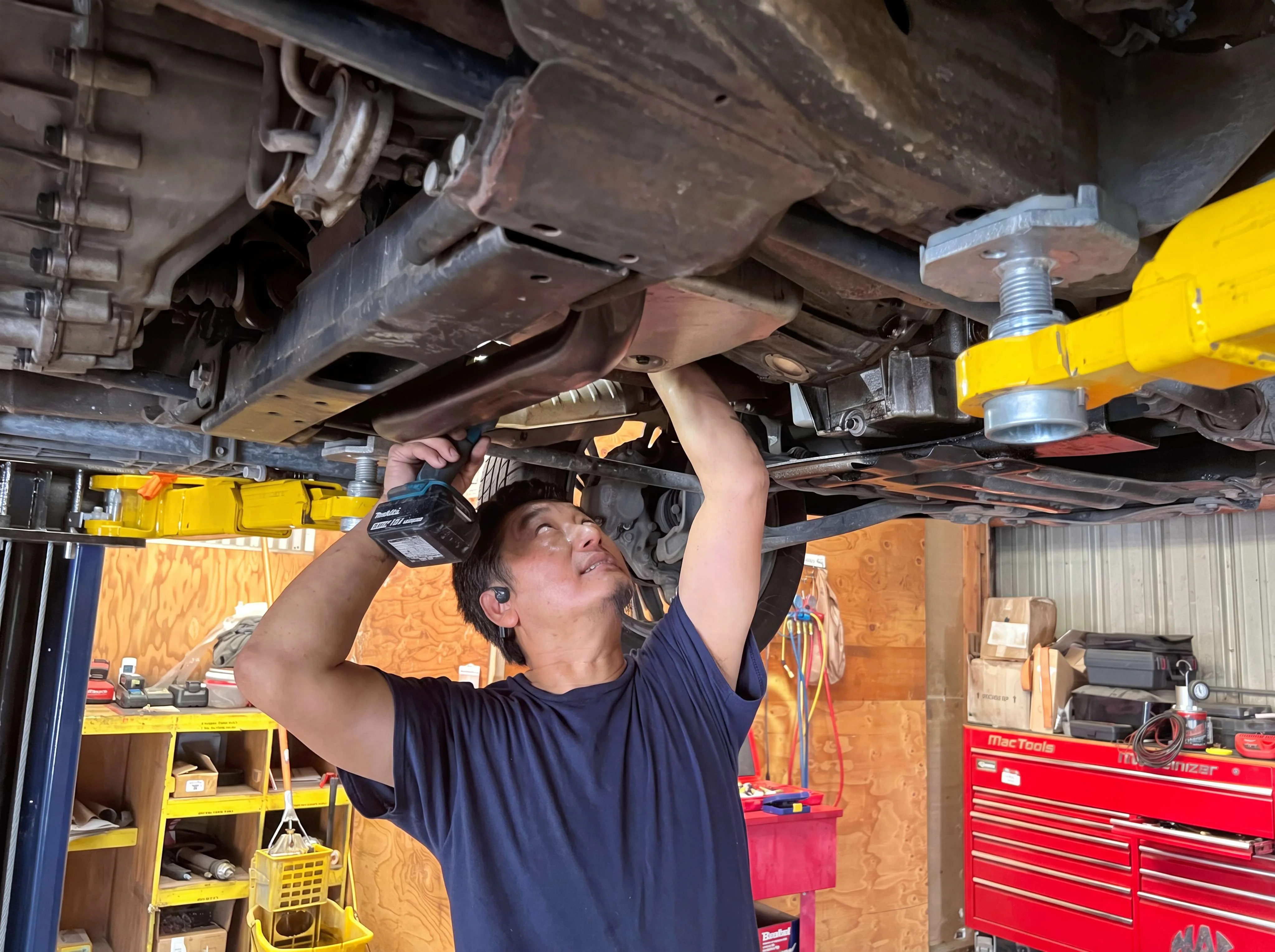 Technician working under a vehicle on a lift at I Care Automotive