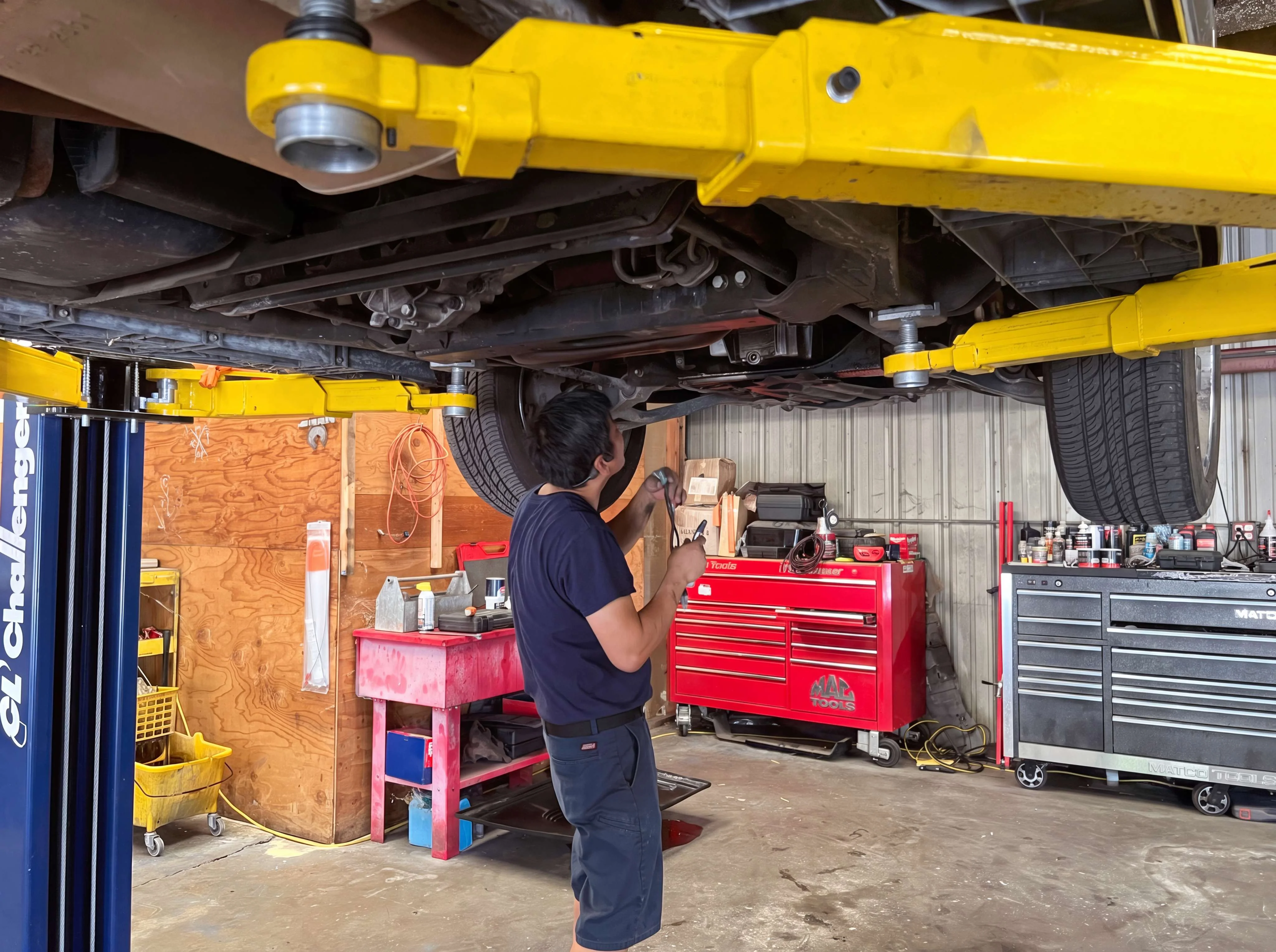 Technician working under a vehicle on a lift at I Care Automotive